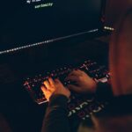 Une personne portant un sweat à capuche tapant sur un clavier avec un écran d'ordinateur affichant un message de curiosité.