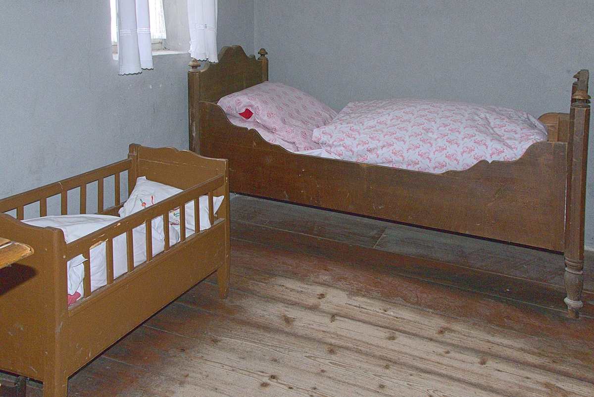 Chambre aménagée avec un lit adulte et un petit berceau en bois clair pour enfant Chambre aménagée avec un lit adulte et un petit berceau en bois clair pour enfant