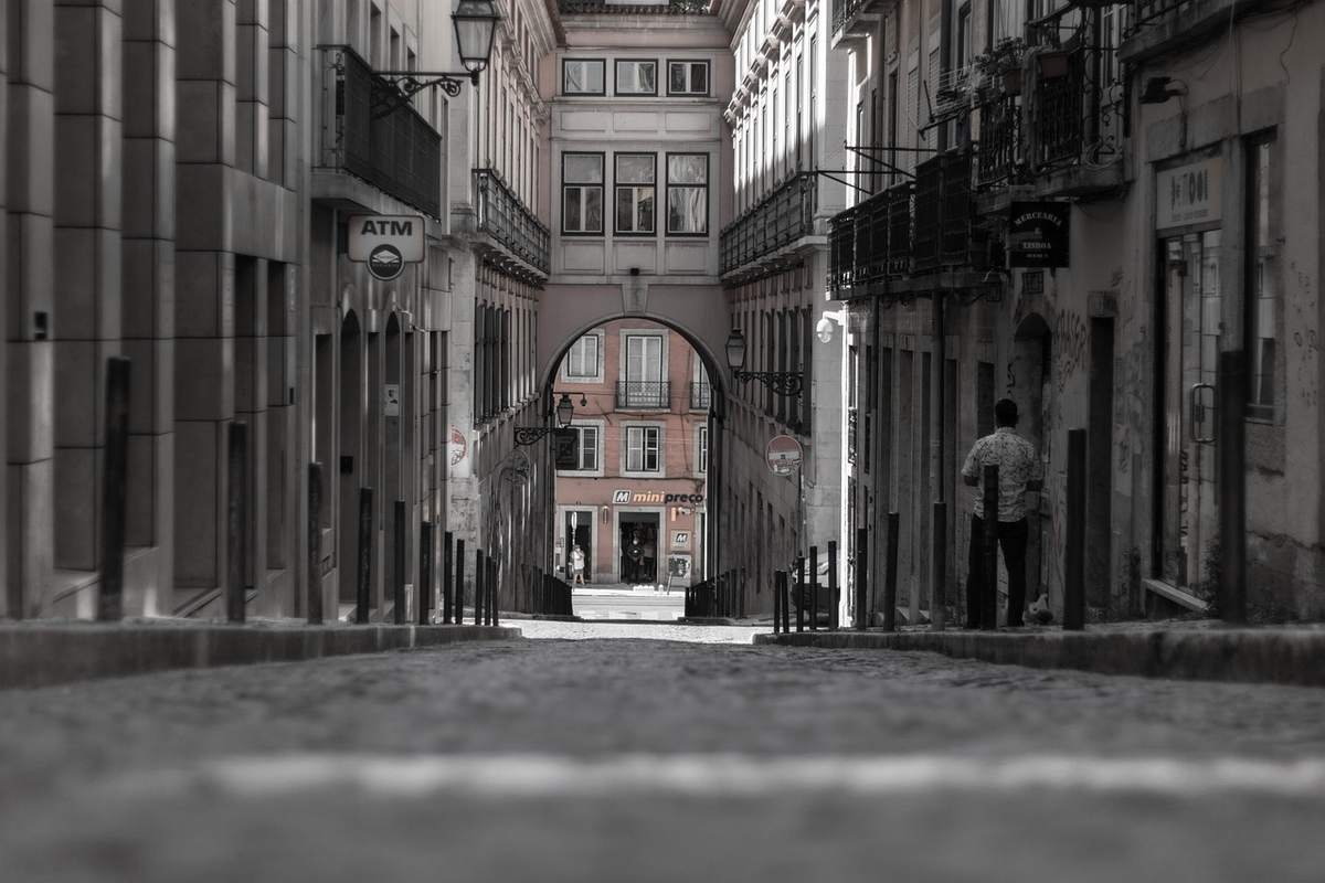 Rue piétonne étroite de Lisbonne bordée d'immeubles anciens avec arche au fond Rue piétonne étroite de Lisbonne bordée d'immeubles anciens avec arche au fond