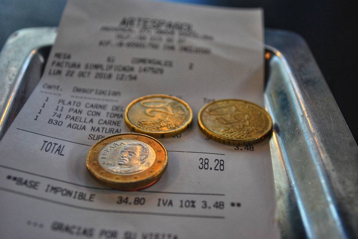Un reçu, trois pièces et une assiette métallique sur plateau