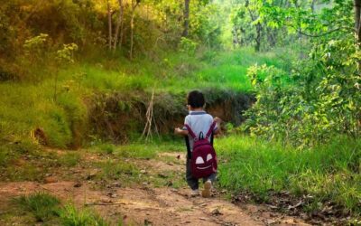 Un petit garçon avec sac à dos marche sur un chemin de terre