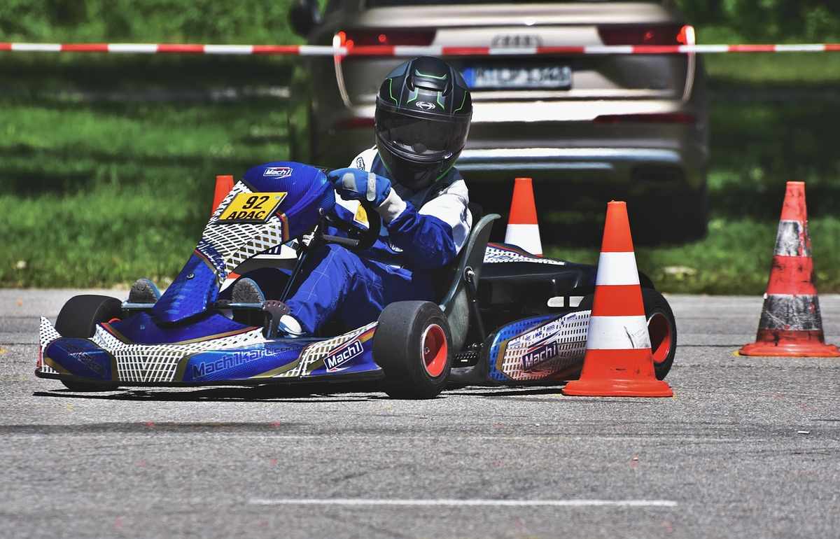 Un pilote en combinaison bleue pilote un kart bleu à travers des cônes