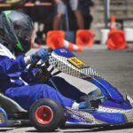 Un coureur en combinaison bleue pilote un kart bleu sur circuit