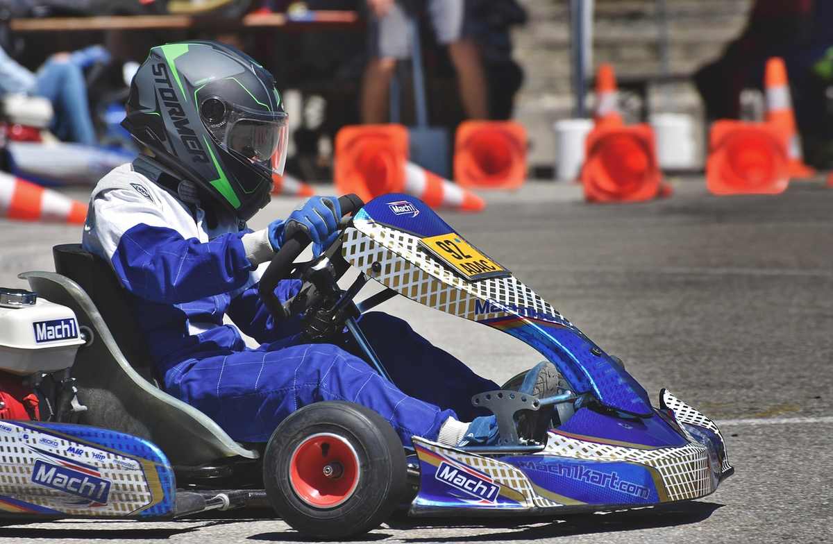 Un coureur en combinaison bleue pilote un kart bleu sur circuit
